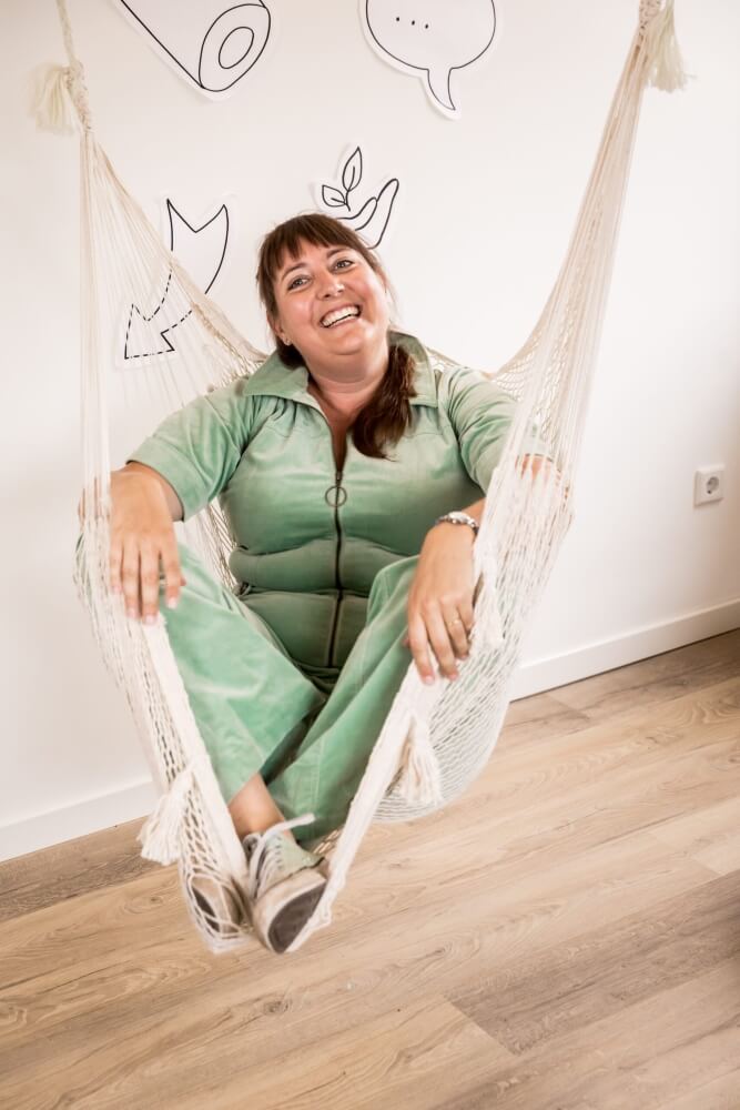Ariënne Wunderink, Zakelijk Tekenaar, vrolijk in een hangmat voor een muur met visuals