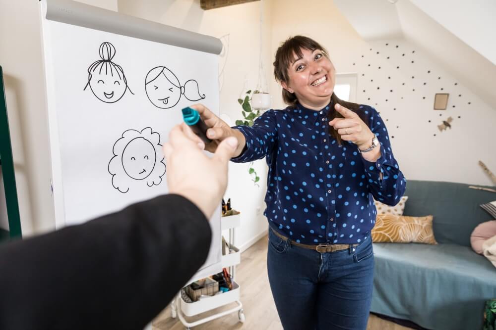Ariënne Wunderink staat voor een flipover met visuals en geeft een stift aan een kersverse tekenaar